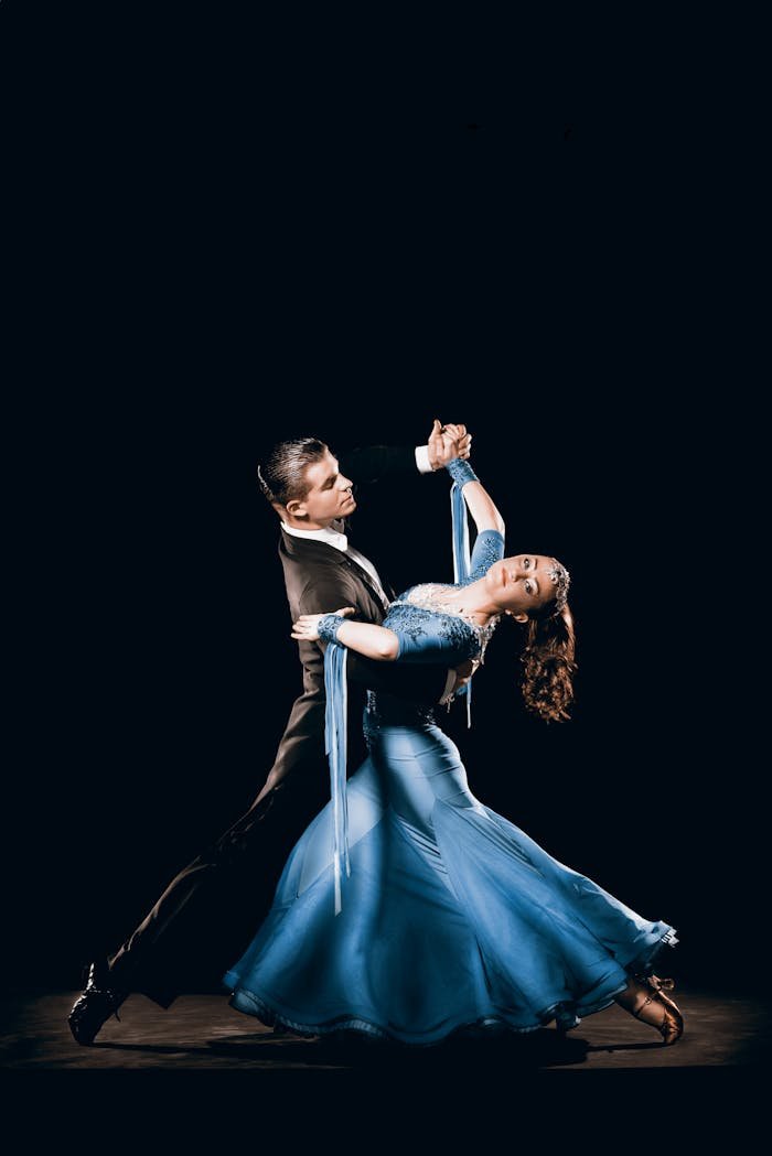 Couple performing a graceful ballroom dance in elegant attire with expressive movements.