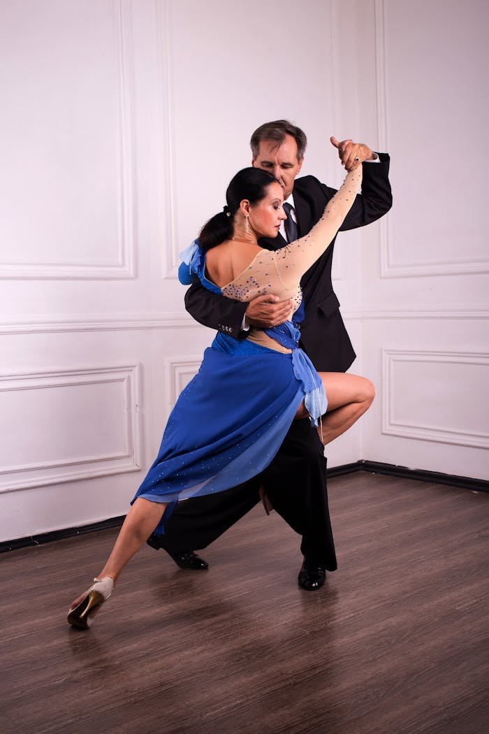 Full body of dancers duet wearing elegant clothes dancing together in corner of modern studio